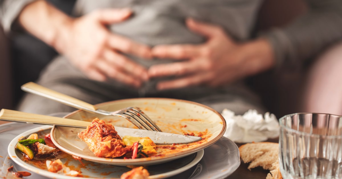 Donna sul divano con le mani sulla pancia dopo il pasto
