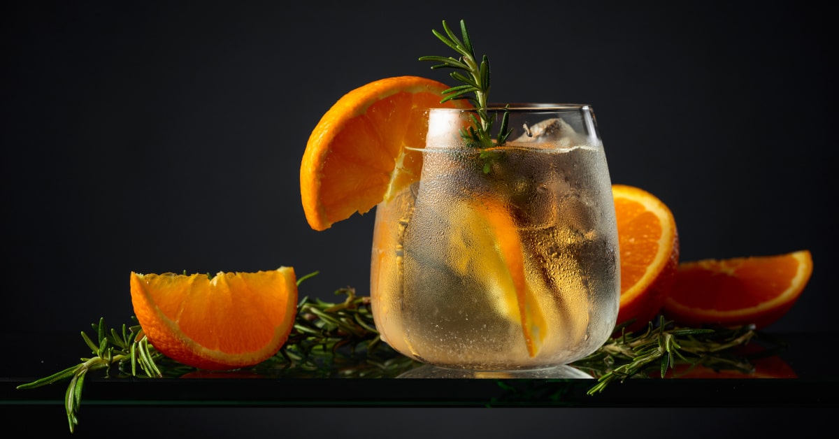 Bicchiere di acqua aromatizzata con fette di arancia e rosmarino