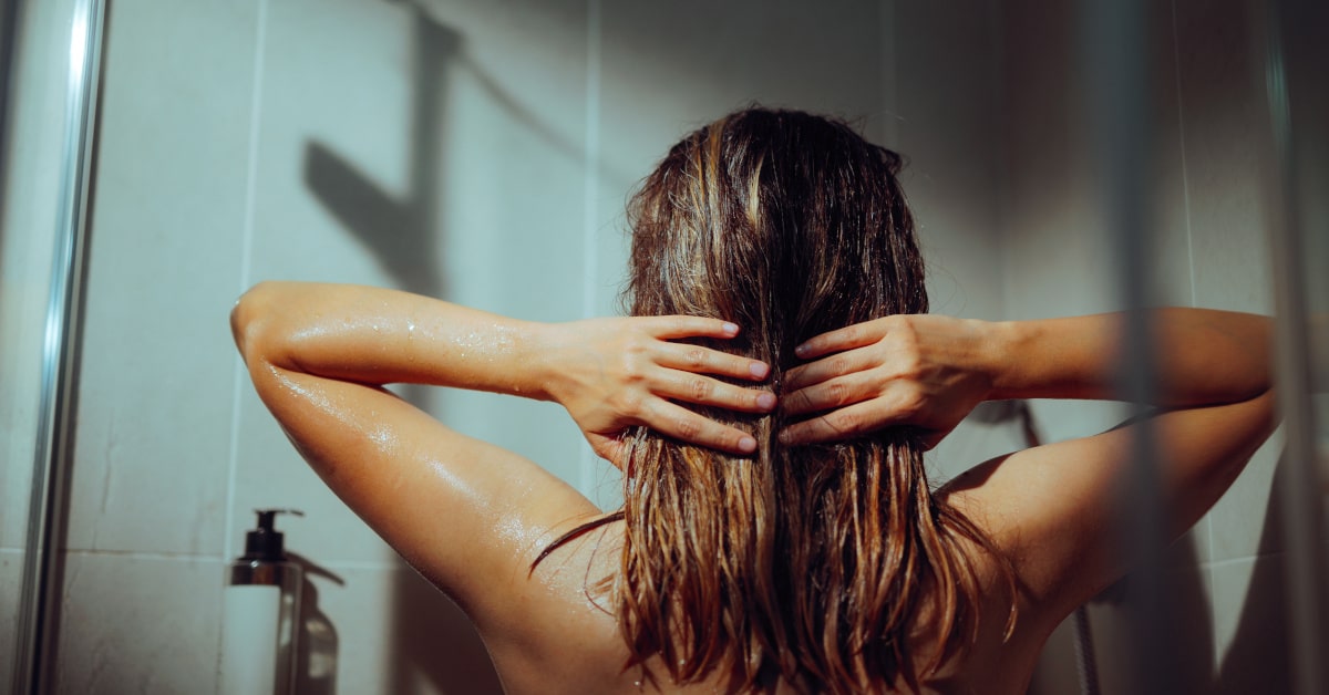 Donna sotto la doccia che lava i capelli