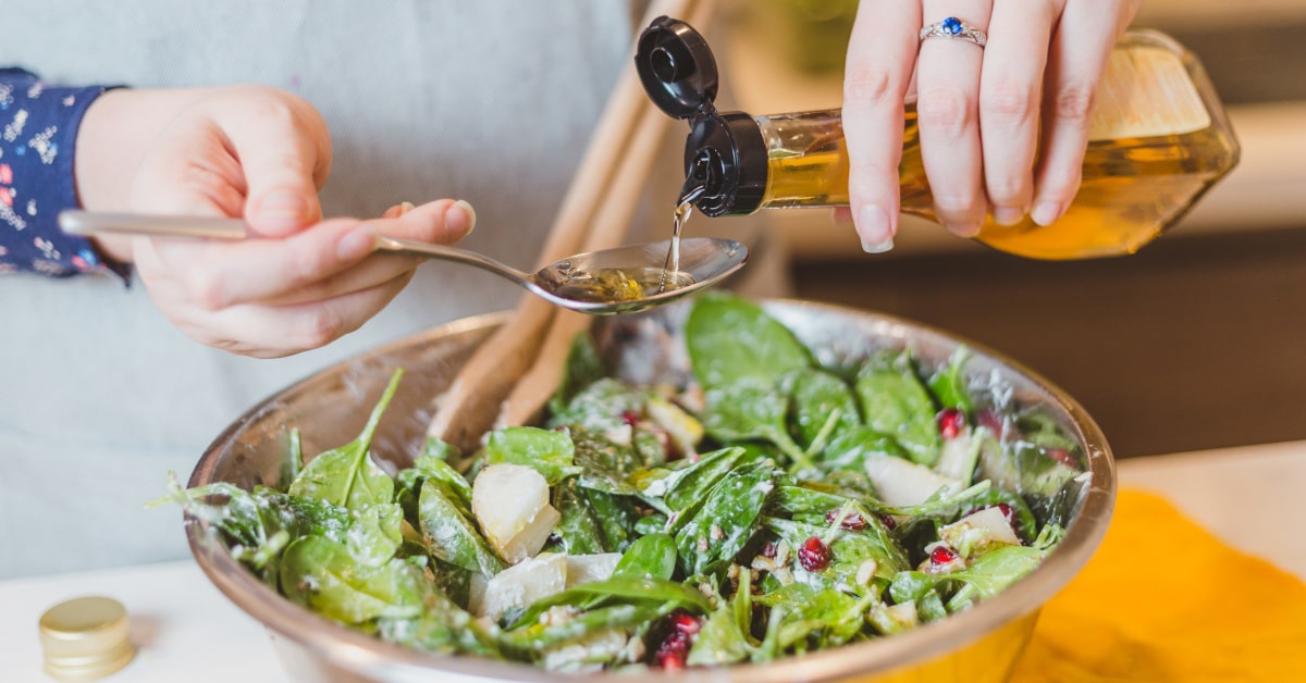 Donna che versa aceto di mele su un piatto di insalata