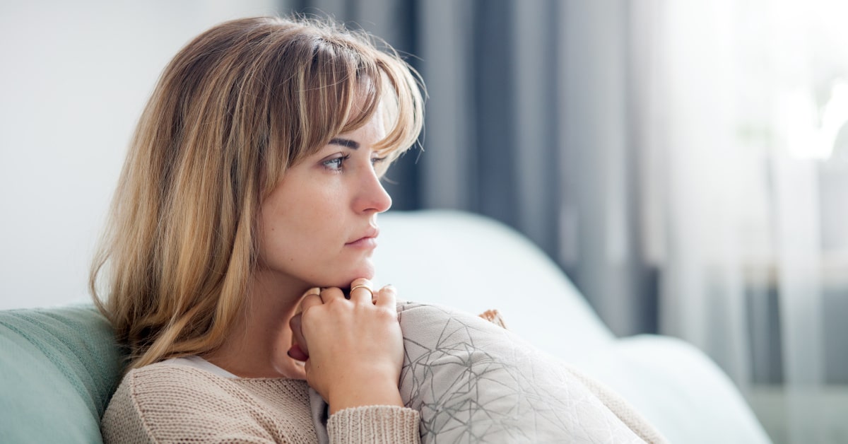 Donna triste e pensierosa sul divano