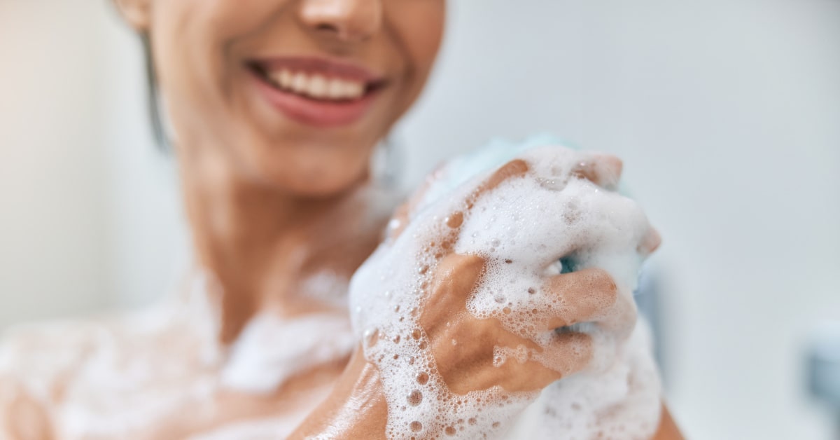 Donna che fa la doccia con spugna in luffa