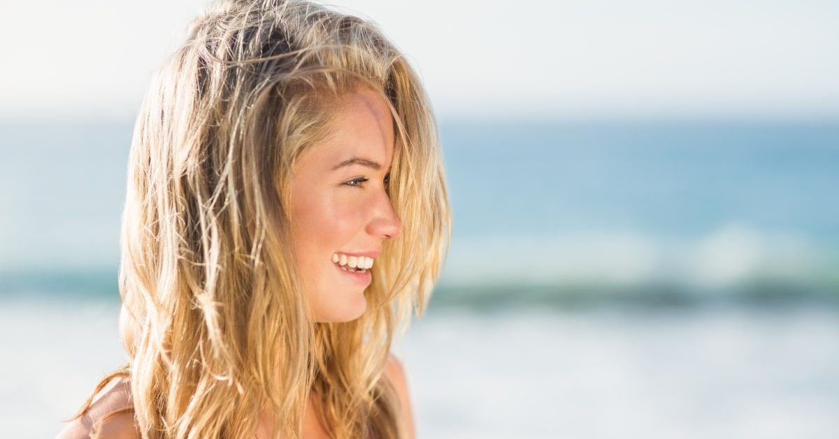 Donna al mare in estate con capelli spettinati