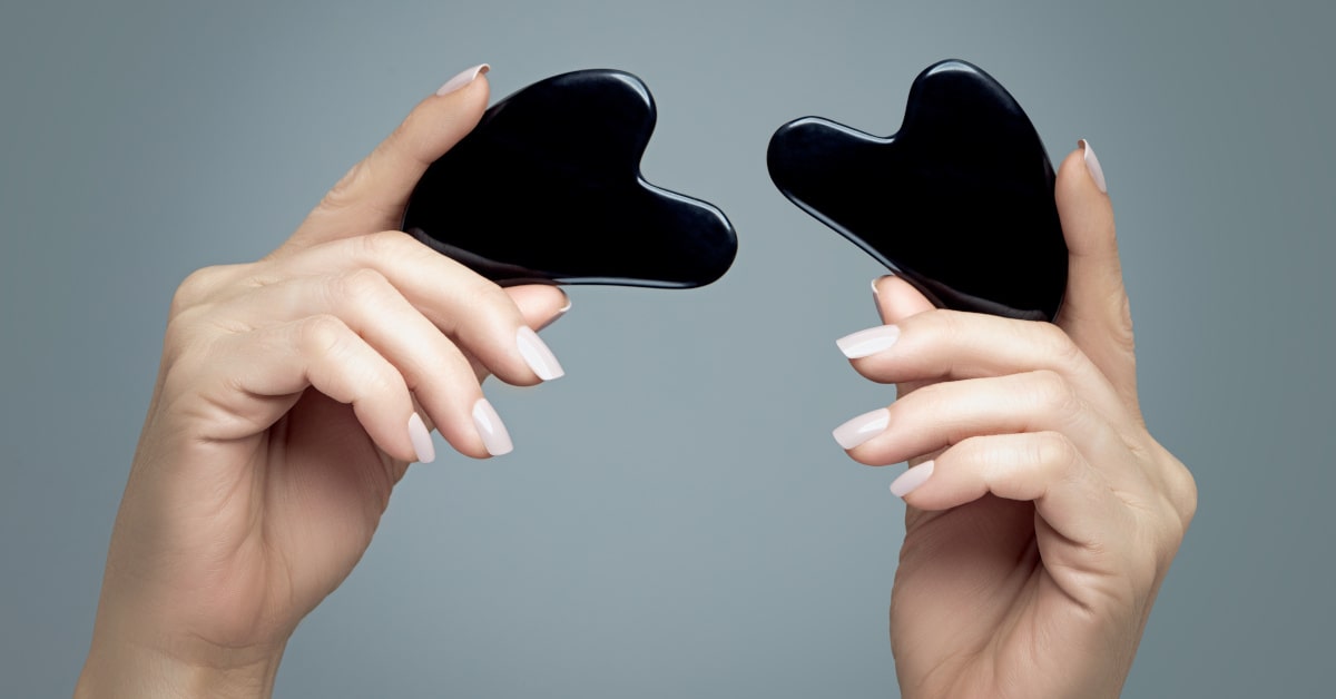 Donna che tiene in mano due pietre di ossidiana nera per gua sha 