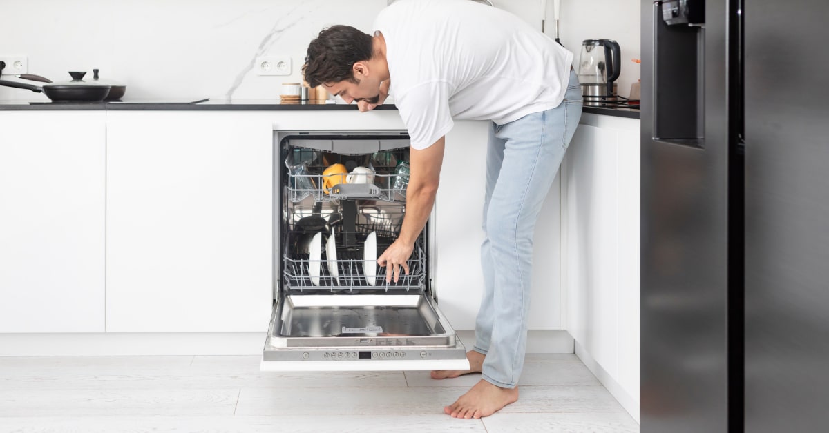 Giovane uomo che riempie la lavastoviglie