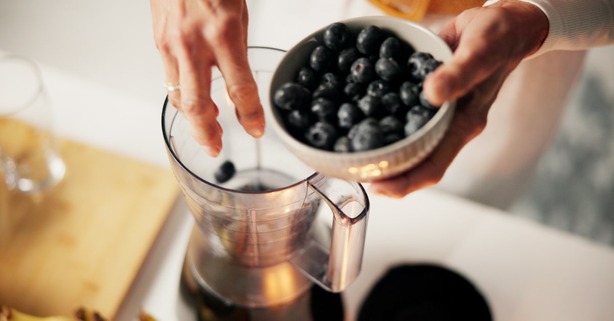 Donna che prepara un frullato con i mirtilli