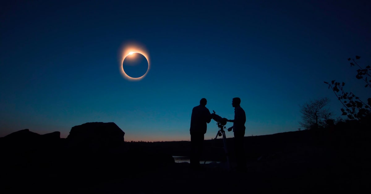 Due persone che stanno osservando una eclissi di sole al telescopio