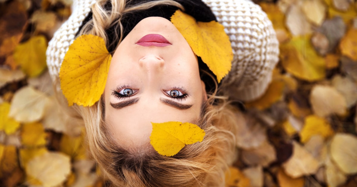 Donna in un parco in autunno con foglie che cadono