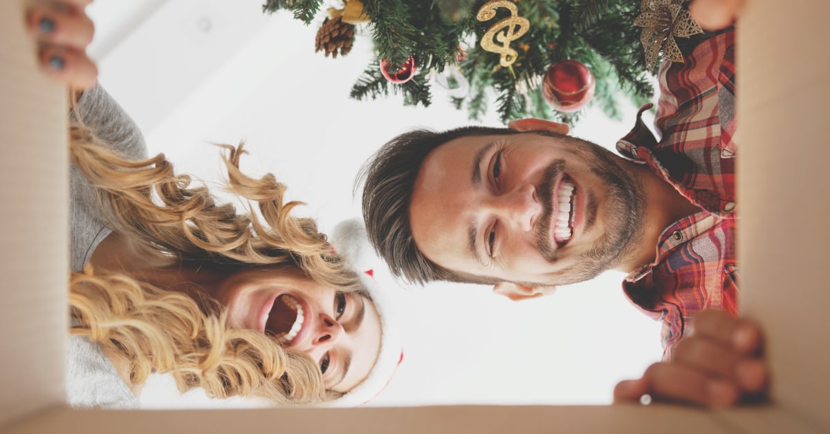 Coppia che guarda felice dentro a un pacco regalo di Natale