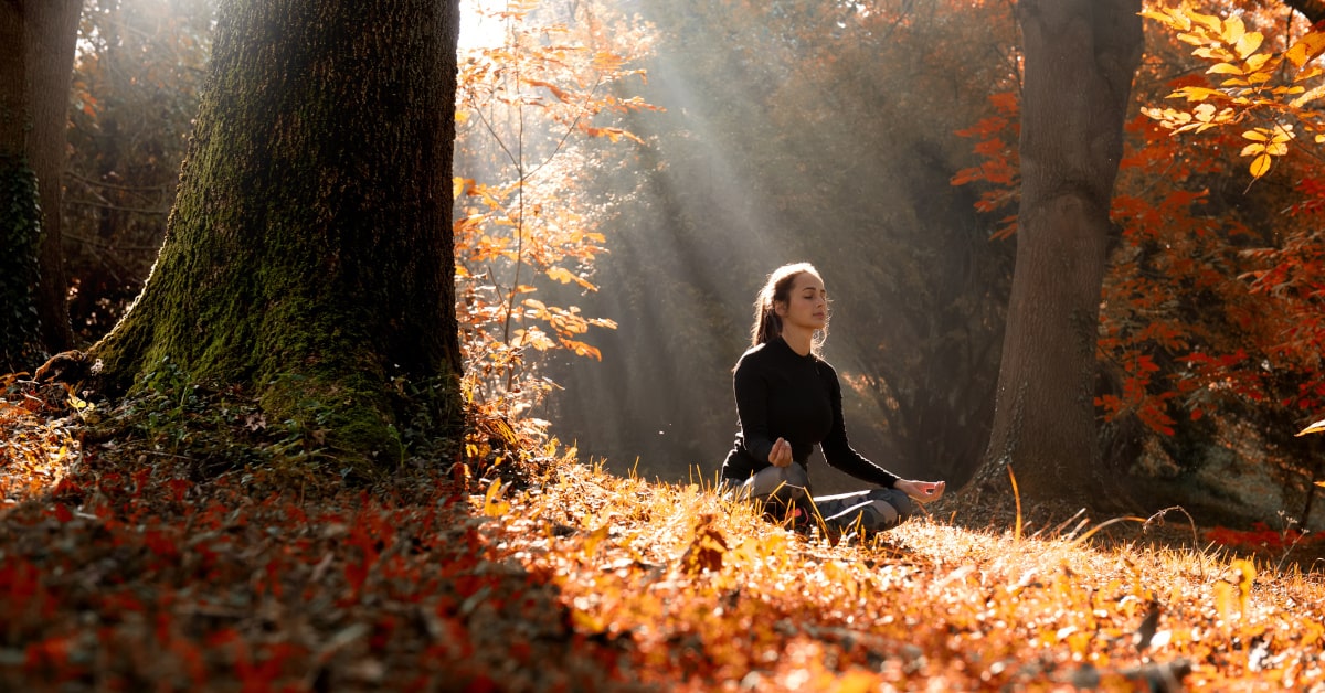 Donna che medita in un bosco in autunno