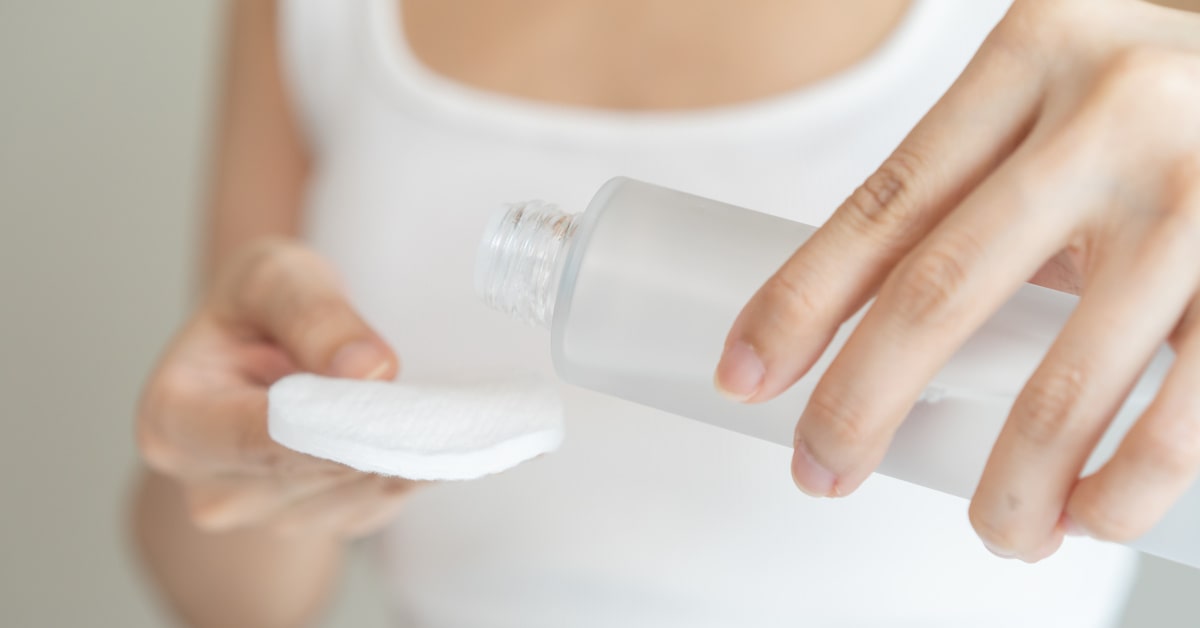 Donna che versa qualche goccia di idrolato su un dischetto di cotone