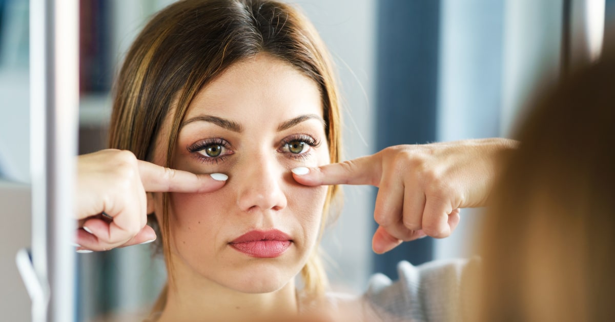 Donna che segnala la presenza di occhi gondi e stanchi con le dita