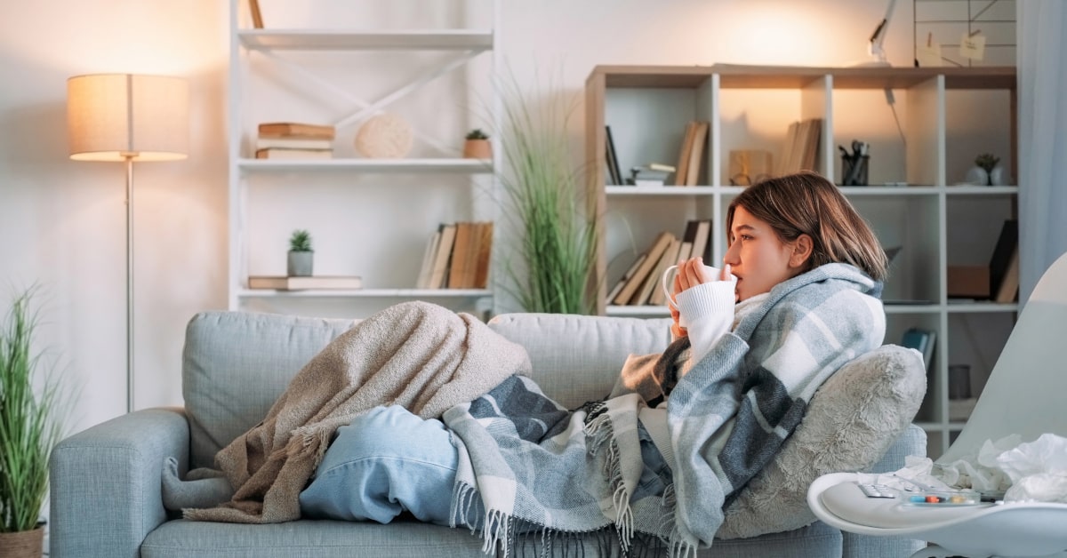 Donna sul divano con sintomi influenzali in inverno