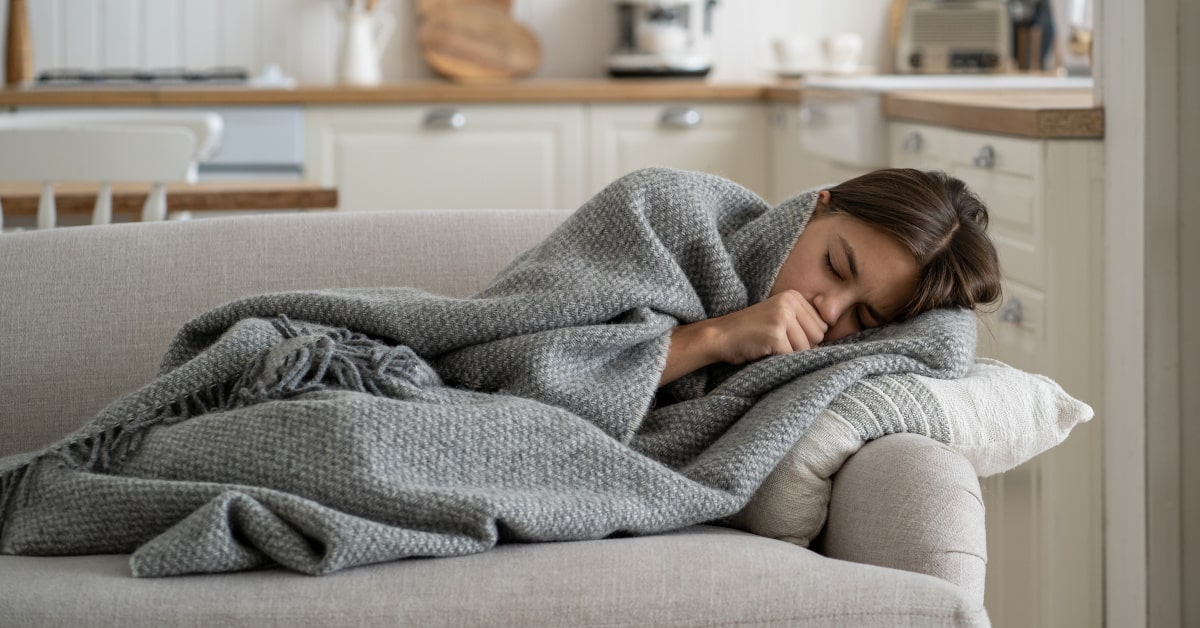 Donna stesa sul divano con tosse e influenza