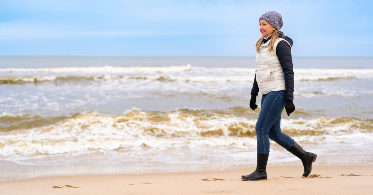 Donna che passeggia sulla spiaggia in inverno