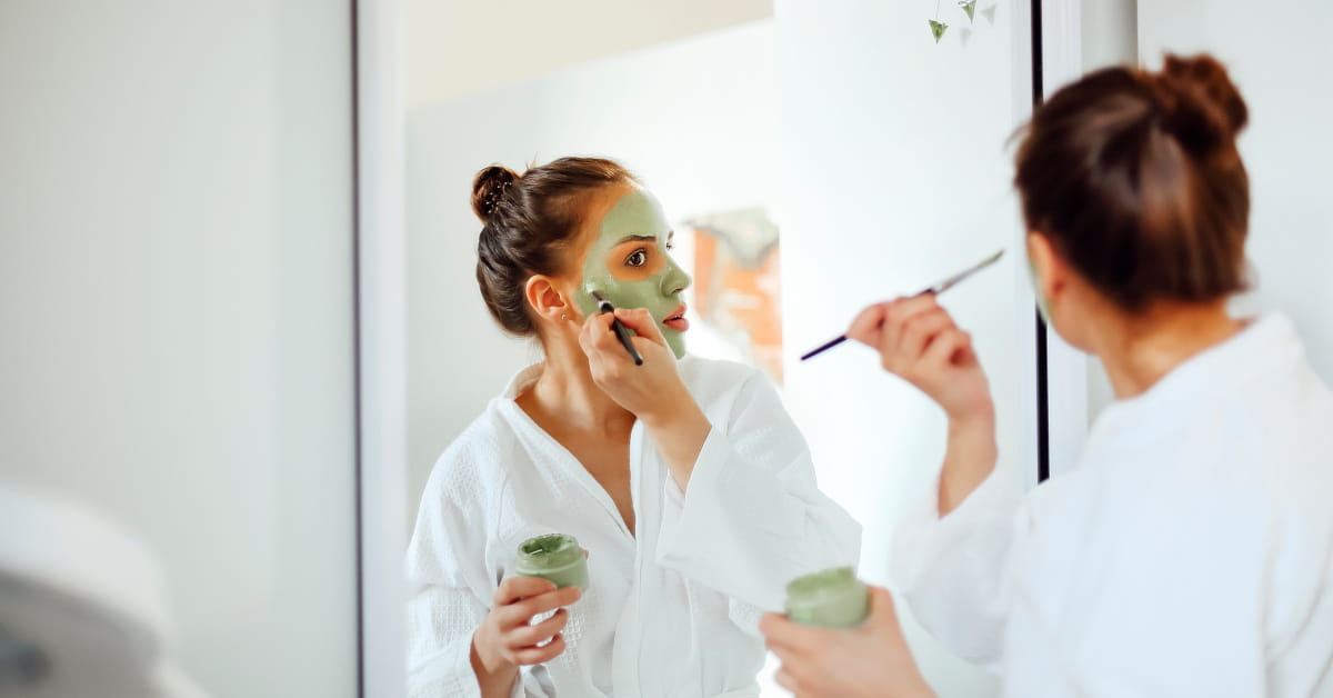 Donna che fa applica una maschera di argilla sul viso
