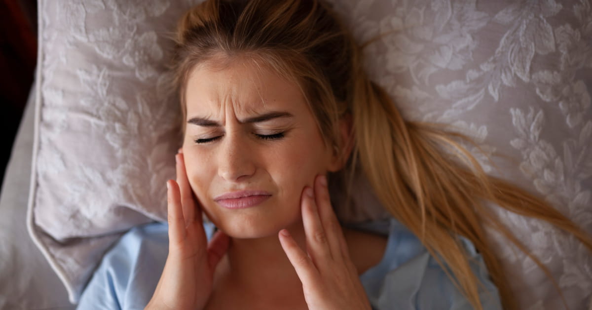 Donna che soffre di bruxismo e dolore mandibolare di notte