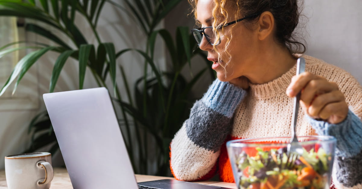 Donna in pausa pranzo davanti al PC con schiscetta