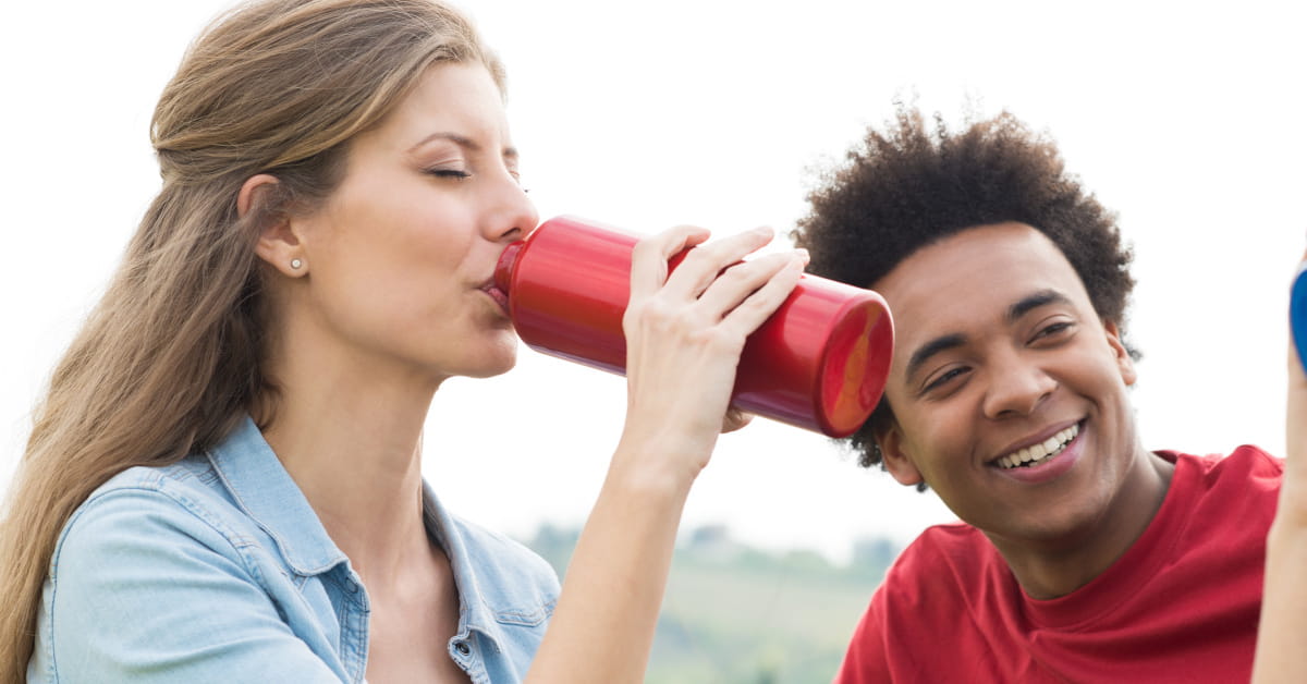 Donna all'aperto che beve da una borraccia di acciao
