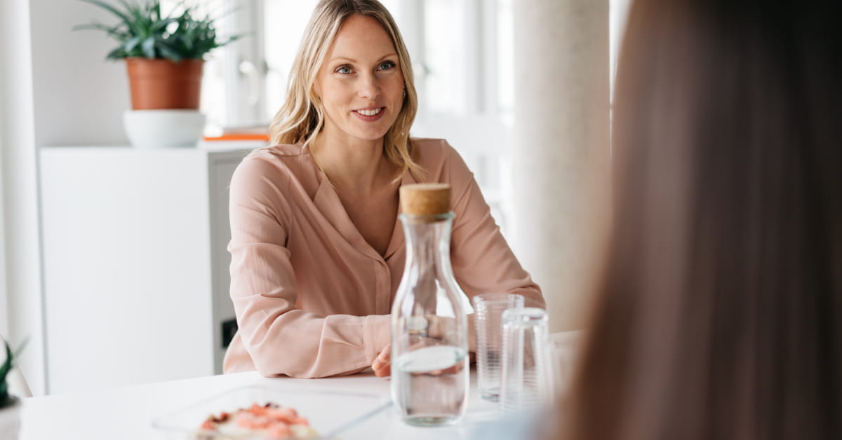 Donna al tavolo con borraccia di vetro