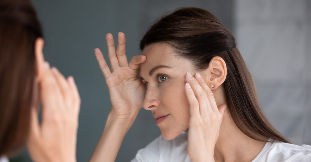 Donna che controlla le rughe del viso allo specchio