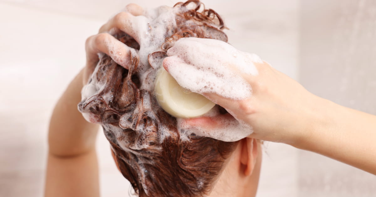 Donna che si lava i capelli con lo shampoo solido