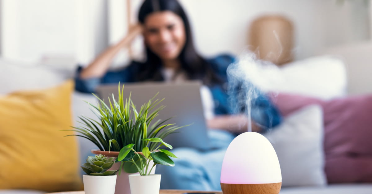 Donna che lavora con diffusore di oli essenziali in salotto