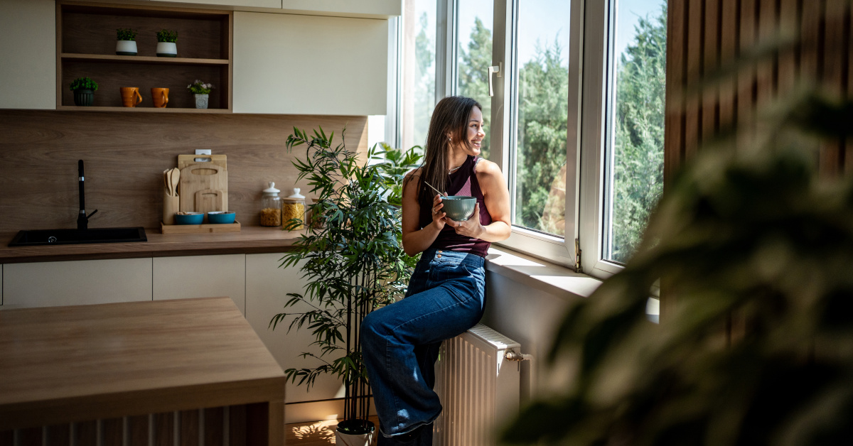 Donna che fa colazione in cucina affacciata alla finestra